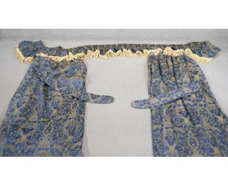 A pair of blue and gold silk mix foliate design curtains with pelmet and tie backs. Silk tassel edging to the pelmet. L.165cm