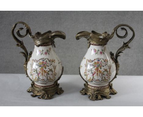 A Pair of Victorian style Wong Lee brass and ceramic jugs. The brass mounts with a scrolling foliate design and the jug paint