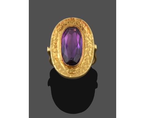 An Amethyst Ring, the oval cut amethyst in a yellow rubbed over setting extending to a textured border, to a tapered shoulder