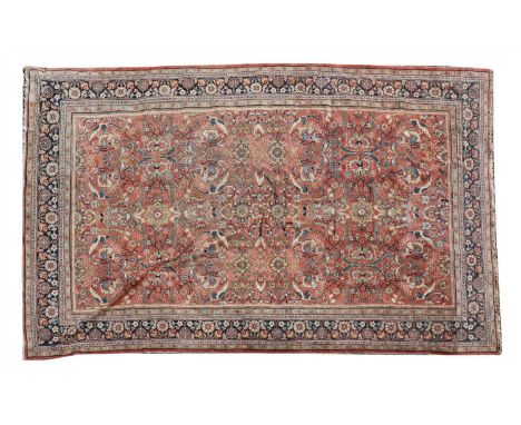 A large Heriz carpet, the red ground with scrolling foliate designs within a blue ground foliate border, 310 x 503cm