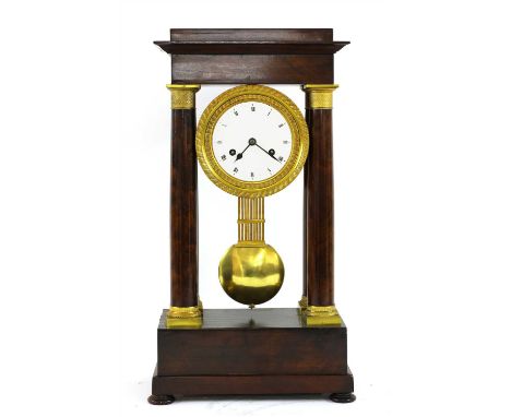 A mahogany French Empire portico clock, 19th century, the enamel dial within gilt metal engine turned mounts and turned colum