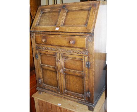 A contemporary moulded and joined oak slopefront writing bureau, having single frieze drawer over conforming panel cupboard d