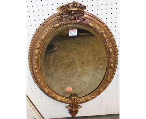 A 19th century giltwood oval wall mirror, having raised fruiting vine border with floral upper and lower surmounts, 68 x 38cm