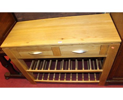 A contemporary light oak two drawer kitchen side table, having twin laddered undertiers, width 110cm