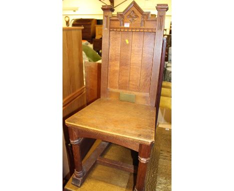 An early 20th century oak Gothic revival panelled seat single hall chair, raised on octagonal cut forelegs to low stretchers 