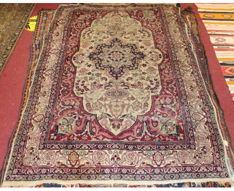 A Persian woollen rug, the cream ground having a central medallion issuing scroll flowers and foliage within trailing tramlin