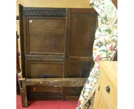 An antique panelled oak double half tester bed, having relief carved and panelled headboard with floral stylised embroidered 