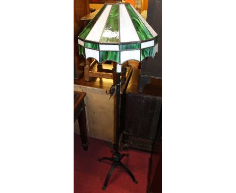A black painted wrought iron standard lamp, having a Tiffany style coloured lead glass dome shade, height 150cm