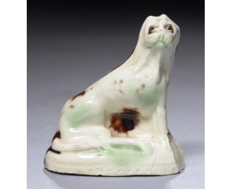 A CREAMWARE TOY MODEL OF A DOG, C1780-1800  seated on a mound and splashed in green and manganese glazes, 6cm h++Several asce