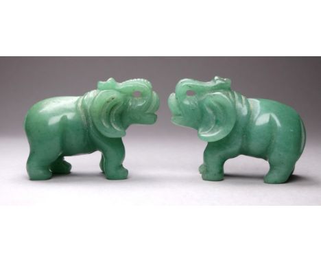 A pair of jade coloured elephants - probably glass, each with their trunk raised, height 4cm.