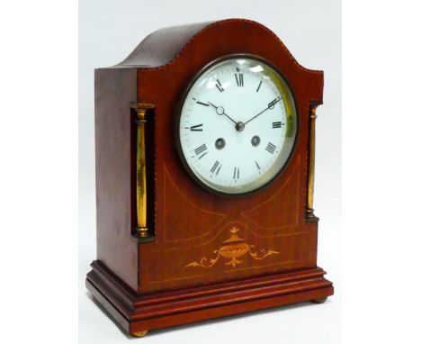 An early 20th century mahogany cased mantel clock - the arched case with brass pilasters and classical inlay, the white ename