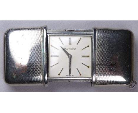 A Mavado travelling timepiece - with engine turned white metal case, the silvered dial with baton numerals, width when open 8
