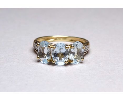 A three stone 9ct yellow gold dress ring - the aqua coloured stones claw set with diamond studded shoulders, ring size K, wei