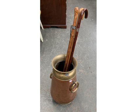 A copper and brass stick stand, 52cmH, with three walking sticks, one with silver collar 