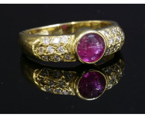A ruby and diamond ring,with a circular cabochon ruby, rub set to the centre, with pavé set diamond shoulders.  Marked 750 18