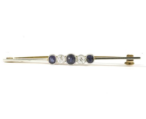 A gold sapphire and diamond bar brooch, three oval cut sapphires between two old cut diamonds milligrain set to a bar brooch,