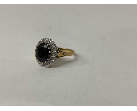 9ct gold Sapphire and diamond cluster ring with an oval mixed cut dark blue sapphire surrounded by a border of single cut dia