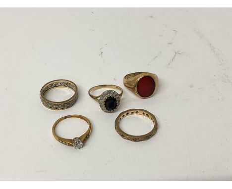 Five 9ct gold rings to include a diamond single stone ring, sapphire and diamond cluster ring, signet ring, and two eternity 