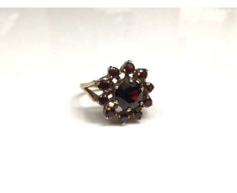 9ct gold garnet cluster ring with a flower head cluster of eleven mixed cut garnets in gold claw setting on 9ct gold shank. R