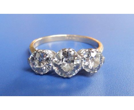 A three stone diamond ring, the central  old cut brilliant weighing approximately .75 carat in white metal claws to yellow me