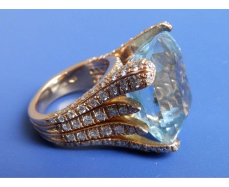 A large aquamrine ring , having asymmetrical stone in yellow 18ct gold claws set with numerous small diamonds (some small sto