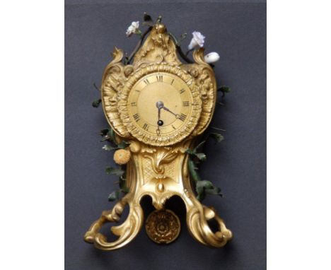 A small Louis XV ormolu mantel clock, the case set with two twisting metal branches mounted with porcelain flowers (some flow