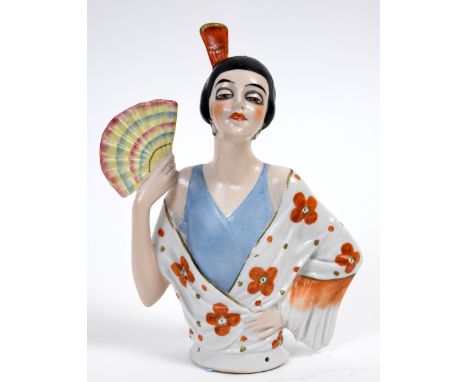A porcelain half doll, Spanish lady with black hair, an orange comb and holding a fan, 15 cm high See illustration 