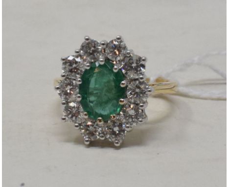 An 18ct yellow gold, emerald and diamond cluster ring, the oval cut emerald of approx. 1.60ct within a surround of eleven dia