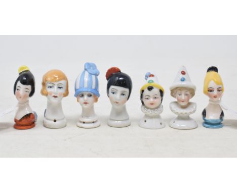 A porcelain half doll head, possibly a brush handle, with blonde hair and a black comb, 6 cm high, and six other heads (7) 