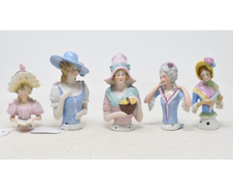 A porcelain half doll, possibly Goebel, lady wearing a yellow bonnet and pink and blue dress, holding a fan, 10.5 cm high, an