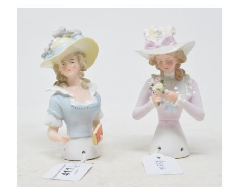 A porcelain half doll, lady wearing a light blue dress and a hat with feathers, holding a book, 13 cm high, and another (2)Re