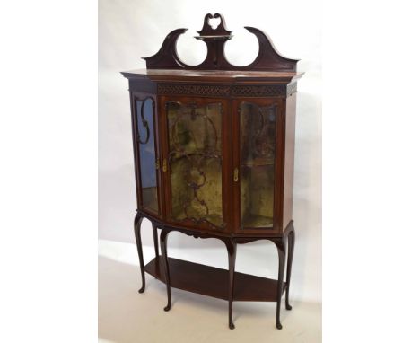 Late Victorian mahogany shaped fronted display cabinet, three glazed doors beneath a fret cut frieze with broken pediment ove