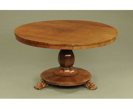 A William IV rosewood breakfast table, circular, with snap action and faceted column, with circular base raised on paw feet w