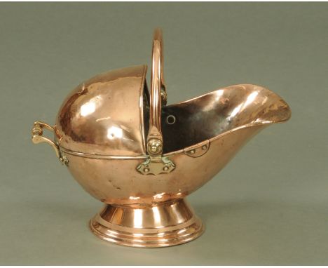 A Victorian copper helmet shaped coal scuttle, supported upon a circular base, 30 cm high.