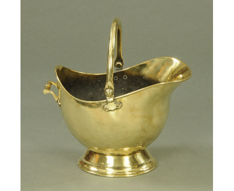 A Victorian brass helmet shaped coal scuttle, supported upon a circular foot, height excluding handle 31.5 cm.