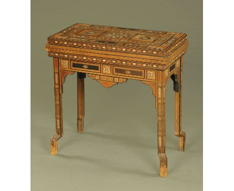 An early 20th century Middle Eastern Moorish design fold over games table, with geometric inlaid decoration and with baize pl