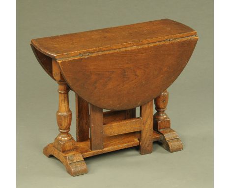 A reproduction oak low drop leaf gate leg table, with turned columns and sledge supports.  Width 60 cm, height 45 cm, width c