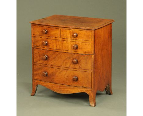 An early 19th century bowfronted commode, modelled as a chest of drawers with wooden knob handles and raised on splayed brack