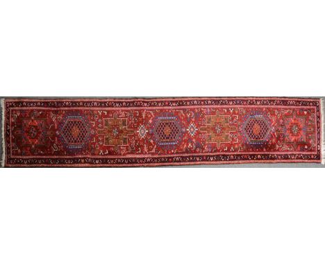 A Belouchi runner, alternating lozenge motifs on a red ground, border within guards, 335 x 71cm.