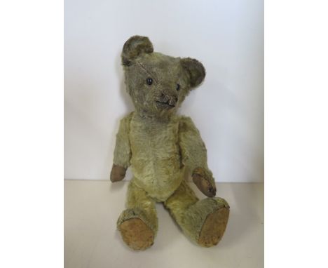 A vintage mohair teddy bear with boot button eyes, 27cm tall, general wear consistent with age, replacement pads and repairs 