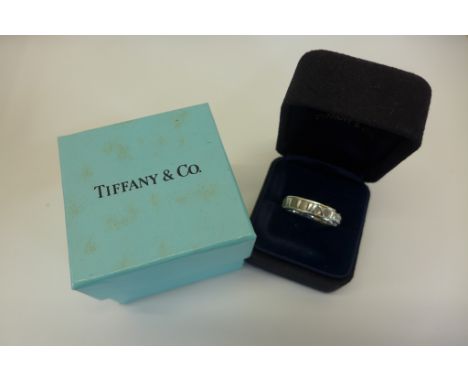 An 18ct white old Atlas ring by Tiffany with a flat section band and series of raised Roman numerals, three brilliant cut dia