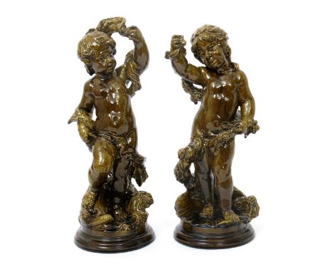 A rare pair of Burmantofts Faience architectural figures of putti, one modelled standing by a classical dolphin, his foot res