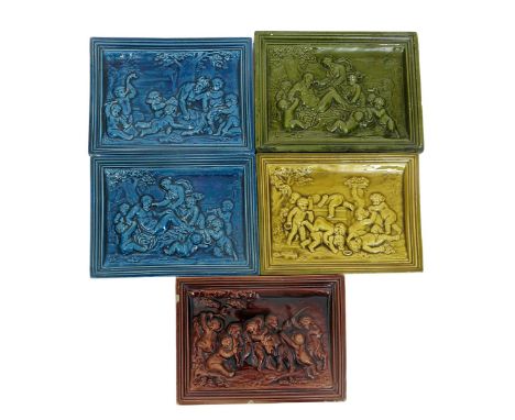 A pair of Burmantofts Faience Bacchanalian tiles,  each modelled in low relief, glazed in blue, another glazed burgundy and t