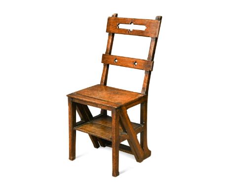 An Arts and Crafts solid walnut metamorphic library chair,  the top and lower back rails both pierced with geometric motifs, 