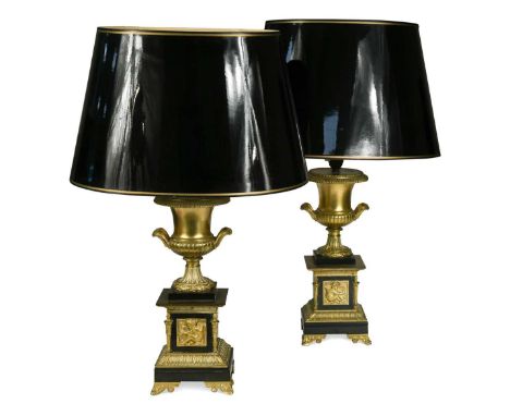 A pair of Empire-style gilt and black painted metal table lamps, each of twin-handled urn form, the fluted socles raised on p