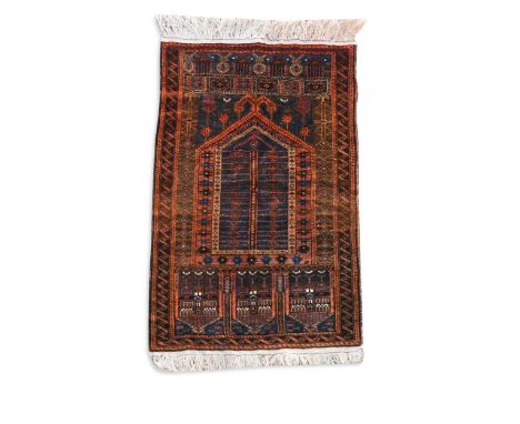 A Beluchi prayer rug, mid-20th century, the intricate mihrab surmounted by a stylised ram's horn within a field of numerous m