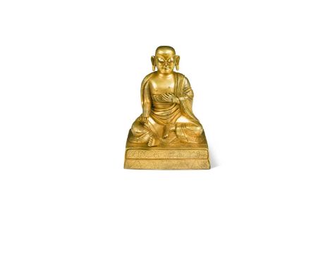 A Chinese or Tibetan gilt bronze figure of a Luohan, seated in meditation upon a square plinth base19cm high