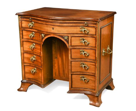 A late George III mahogany and satinwood serpentine kneehole desk, with ormolu mounts, with brushing slide and long frieze dr