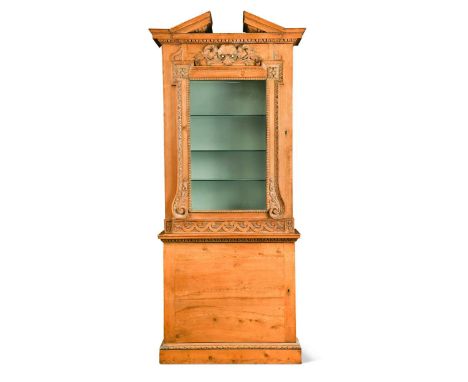 A George II pine pier cabinet in the manner of William Kent, the egg and dart moulded broken arched pediment over a single gl