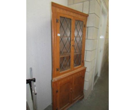 A light oak lead glazed corner cabinet